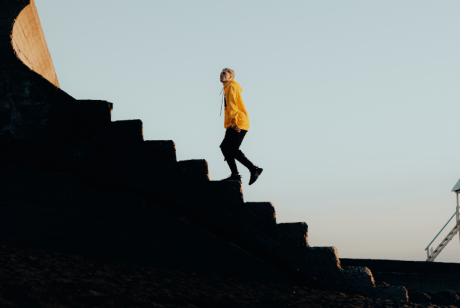A man wearing a hoodie walking upstairs