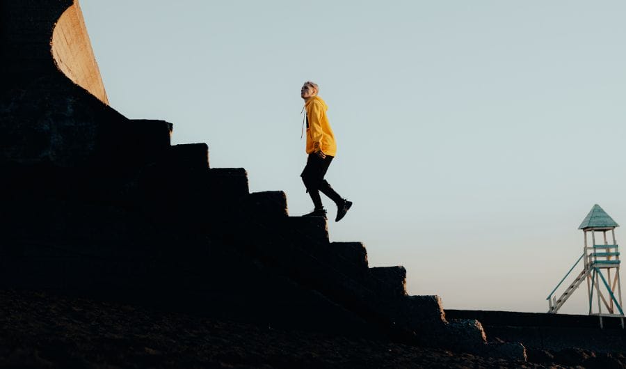 A man wearing a hoodie walking upstairs