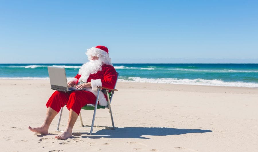 Santa Clause working while vacationing at the beach