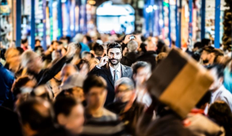A business man making a call in the middle of a crowd